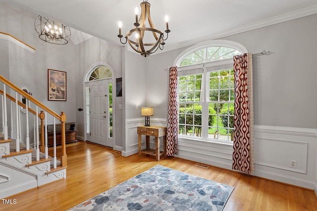 entrance foyer with a notable chandelier, light hardwood / wood-style floors, and ornamental molding