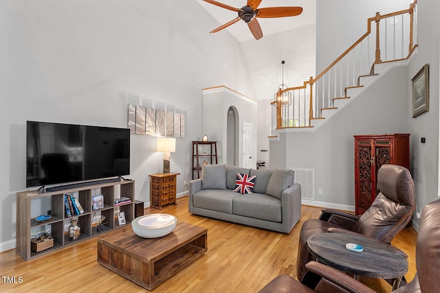 living room featuring ceiling fan with notable chandelier, hardwood / wood-style flooring, and high vaulted ceiling