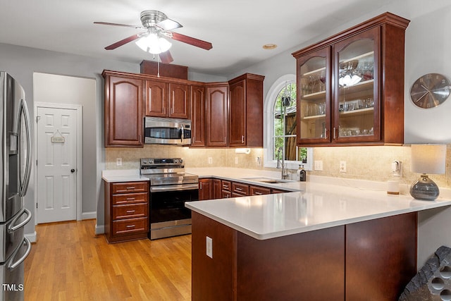 kitchen with sink, kitchen peninsula, stainless steel appliances, and light hardwood / wood-style flooring