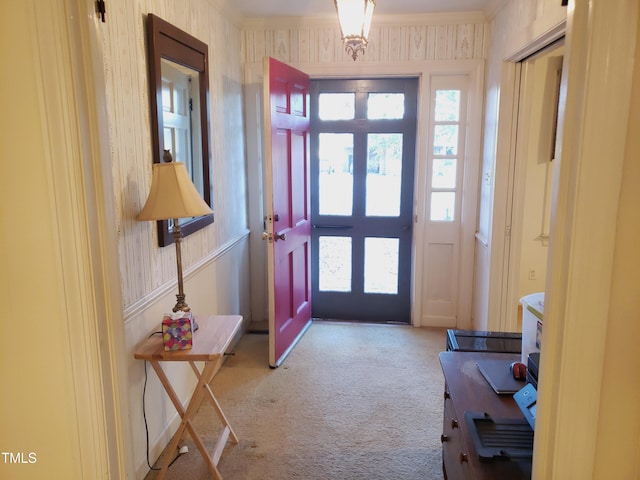 carpeted foyer entrance featuring french doors, plenty of natural light, and ornamental molding