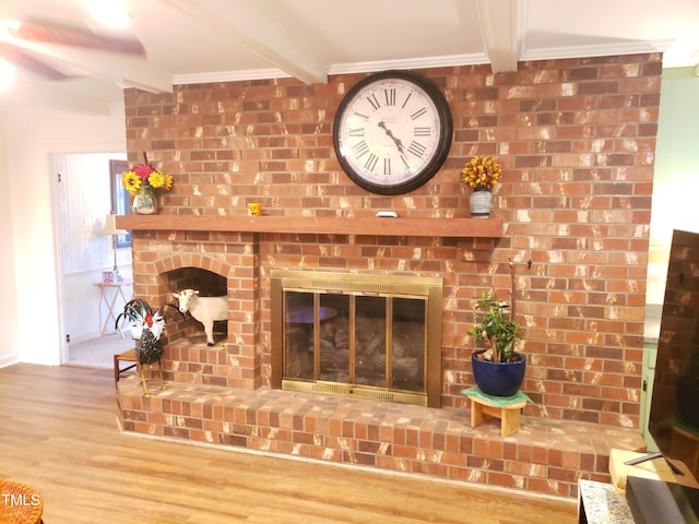 room details featuring beam ceiling, a fireplace, ornamental molding, and hardwood / wood-style flooring