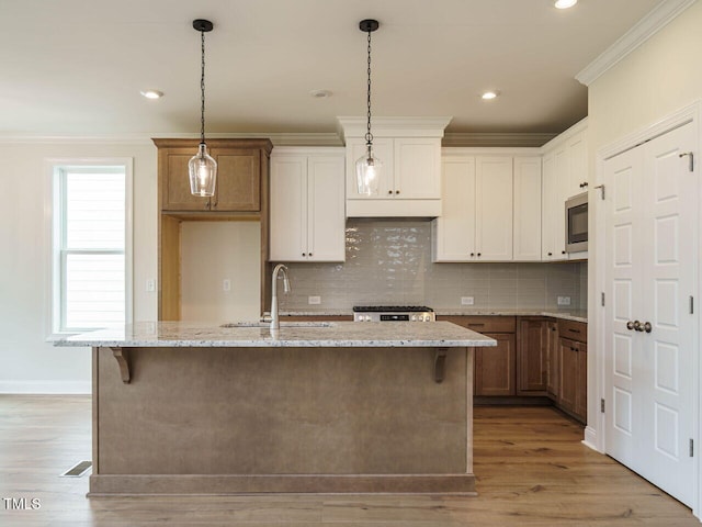 kitchen with white cabinetry, sink, light hardwood / wood-style floors, and a center island with sink