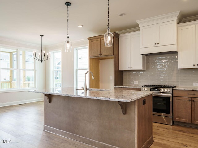 kitchen featuring white cabinets, light stone countertops, light hardwood / wood-style floors, an island with sink, and gas stove