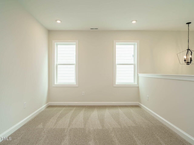 carpeted spare room featuring a notable chandelier