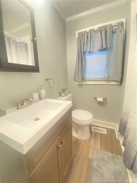 110 N Grove Ave, Rockingham, NC 28379 - full bathroom with crown molding, wood finished floors, vanity, toilet, and baseboards
