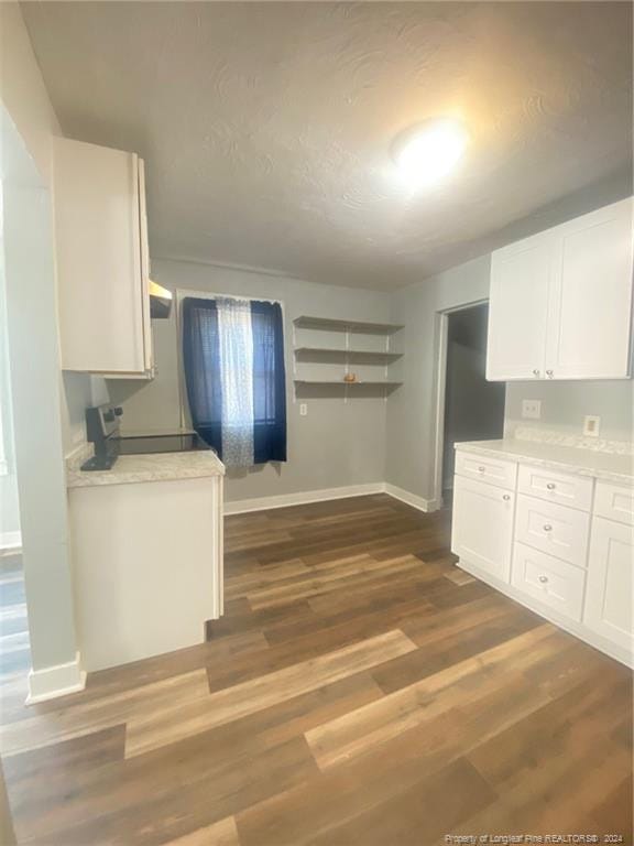110 N Grove Ave, Rockingham, NC 28379 - kitchen with white cabinets, light countertops, baseboards, dark wood-type flooring, and stove