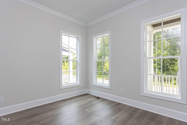 empty room featuring ornamental molding, dark wood-style flooring, visible vents, and baseboards