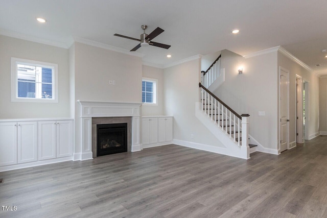 unfurnished living room featuring plenty of natural light, stairway, and wood finished floors