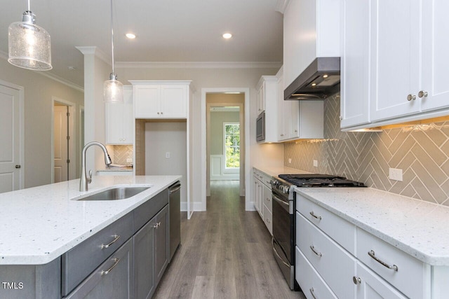 kitchen with a sink, white cabinets, ornamental molding, wall chimney range hood, and appliances with stainless steel finishes