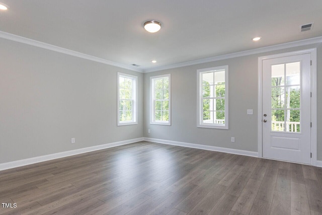 empty room featuring ornamental molding, dark wood-style flooring, and a healthy amount of sunlight