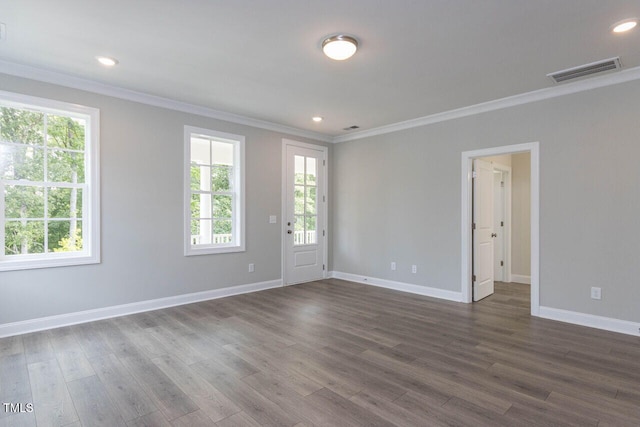 empty room with dark wood-style floors, baseboards, visible vents, and ornamental molding