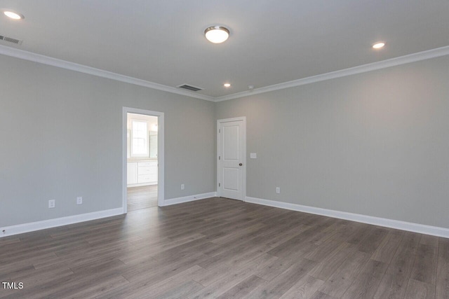 unfurnished room featuring dark wood-style floors, visible vents, crown molding, and baseboards