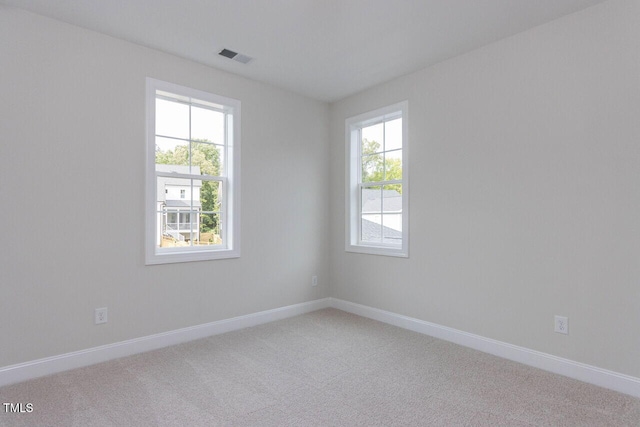 unfurnished room with a healthy amount of sunlight, baseboards, and light colored carpet