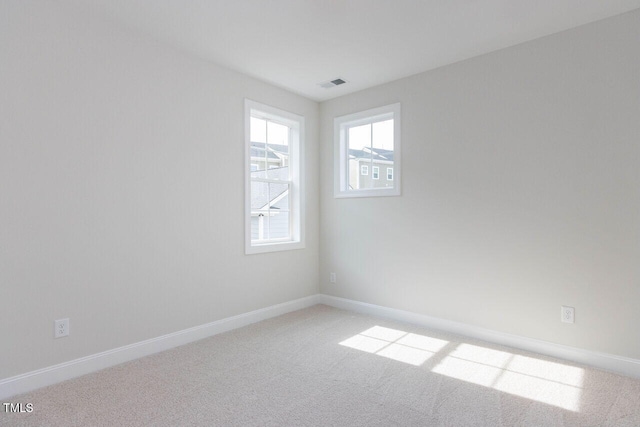 spare room featuring light colored carpet, visible vents, and baseboards