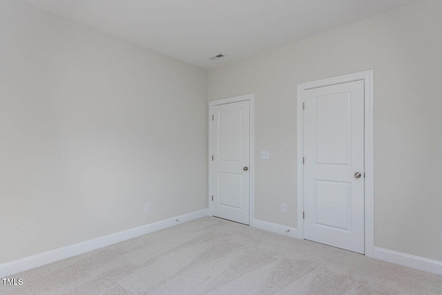 unfurnished bedroom with light carpet, baseboards, and visible vents