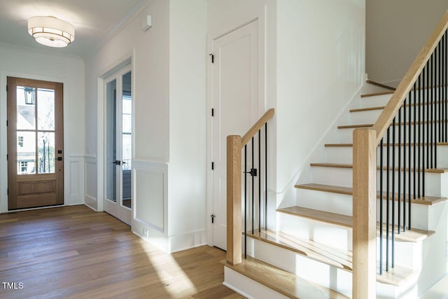 entryway with light wood-type flooring and crown molding