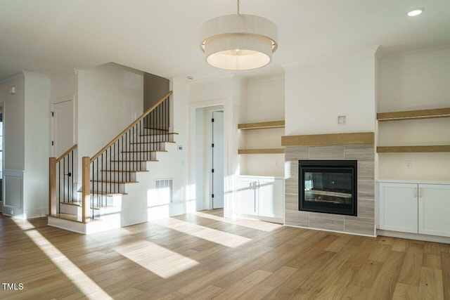 unfurnished living room with a fireplace, crown molding, and light hardwood / wood-style flooring