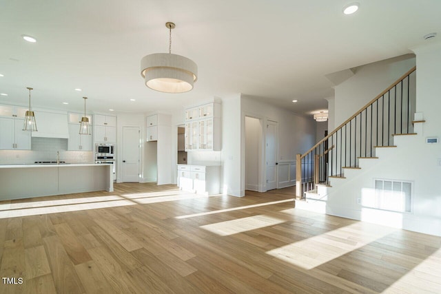 unfurnished living room with sink and light hardwood / wood-style floors