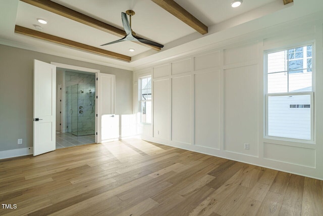 empty room with ceiling fan, a raised ceiling, light wood-type flooring, and ornamental molding