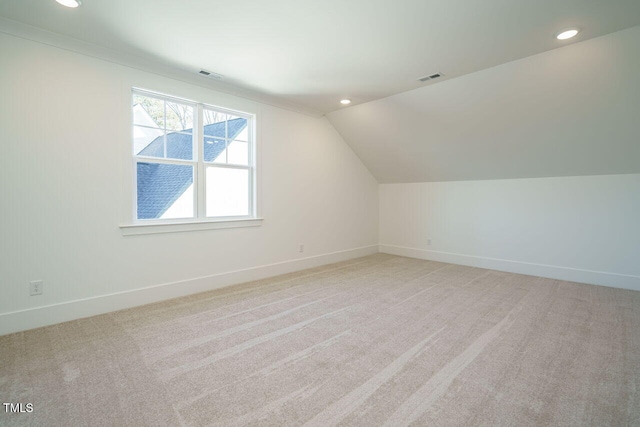 additional living space featuring light colored carpet and vaulted ceiling