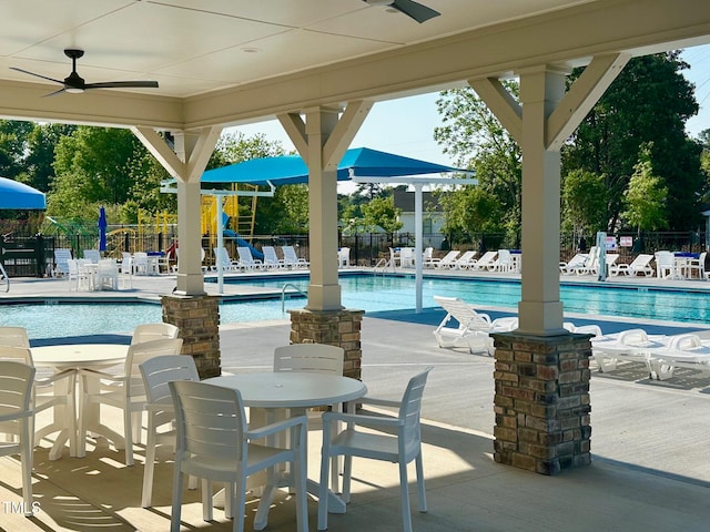 view of swimming pool with ceiling fan, a patio, and a playground