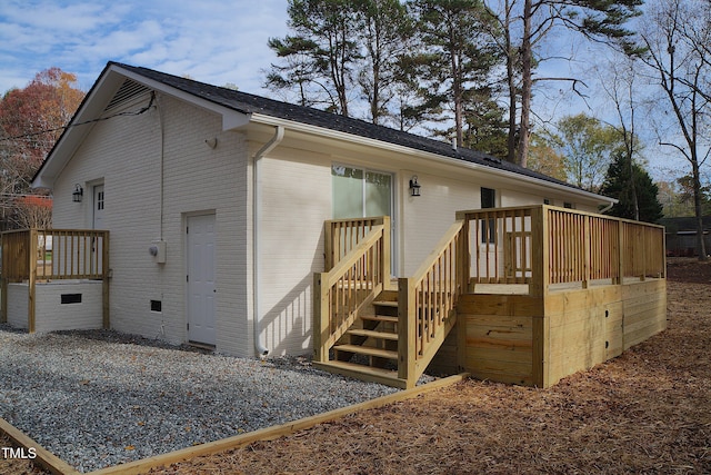 back of property featuring crawl space, a wooden deck, and brick siding