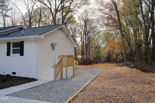 view of side of property with a garage, crawl space, brick siding, and roof with shingles