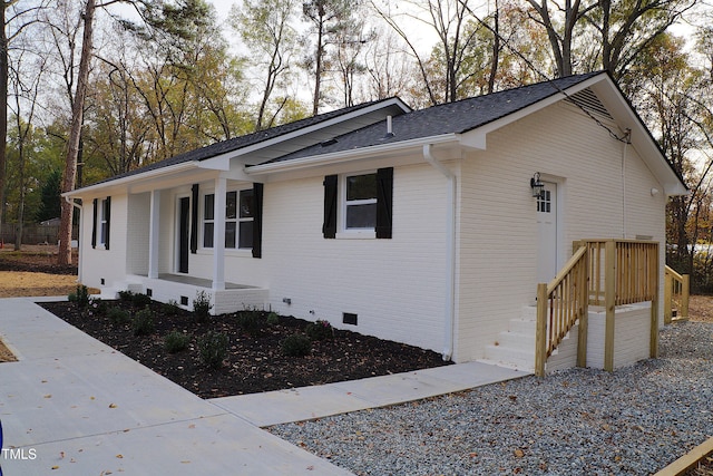 view of property exterior with crawl space, a shingled roof, a porch, and brick siding