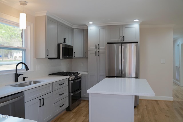 kitchen featuring crown molding, light wood finished floors, stainless steel appliances, light countertops, and a sink