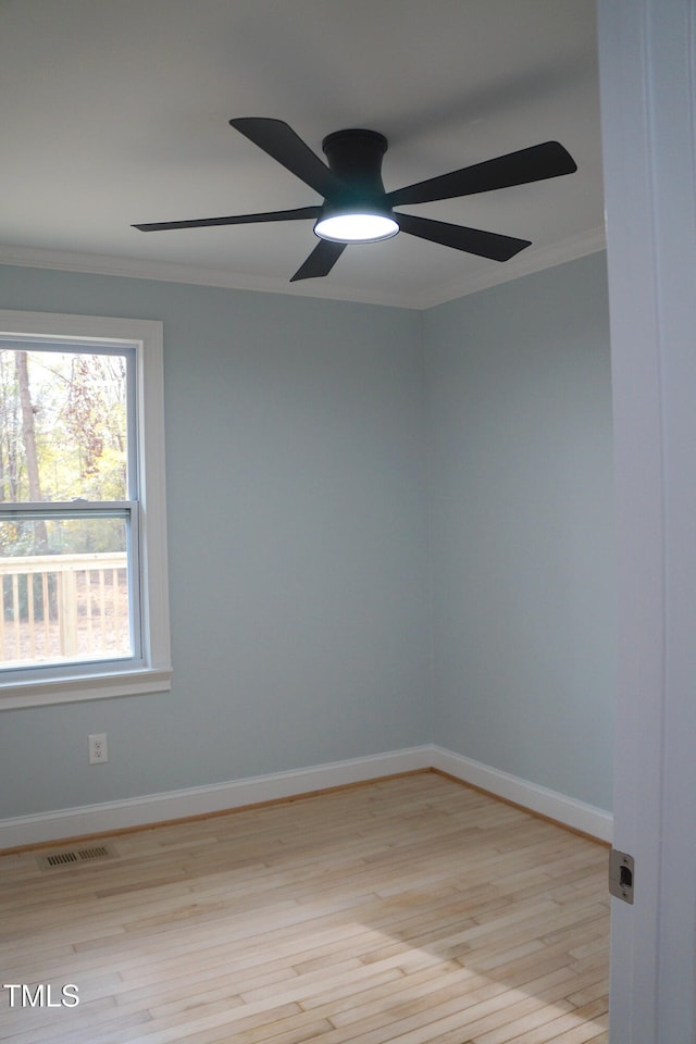 empty room with crown molding, visible vents, light wood-style flooring, a ceiling fan, and baseboards