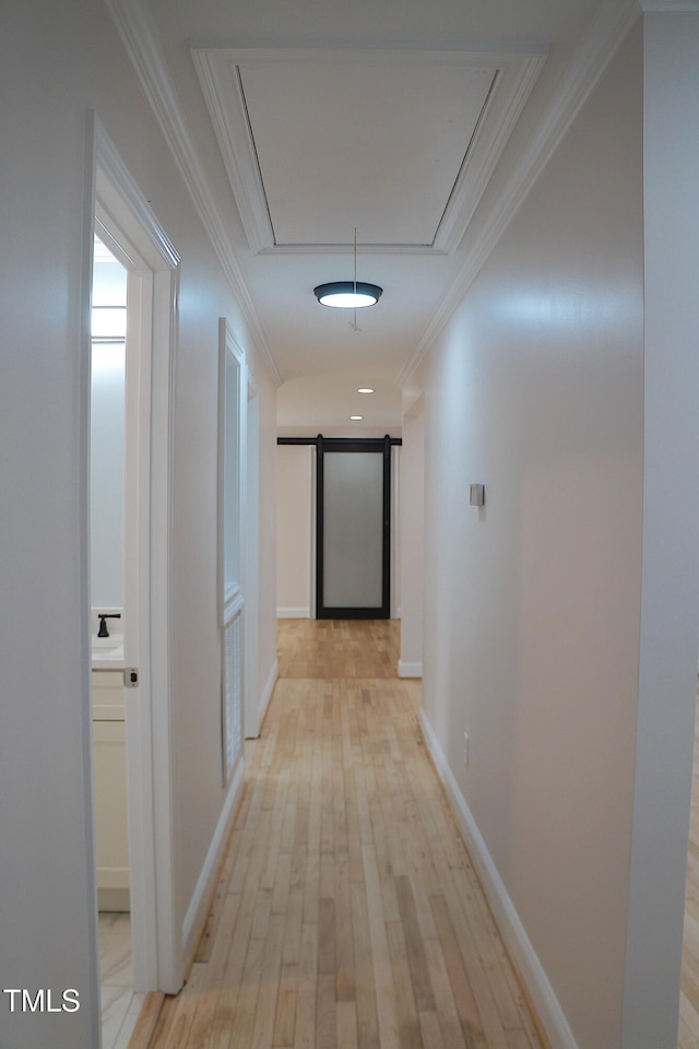 corridor featuring attic access, ornamental molding, light wood-style flooring, and baseboards