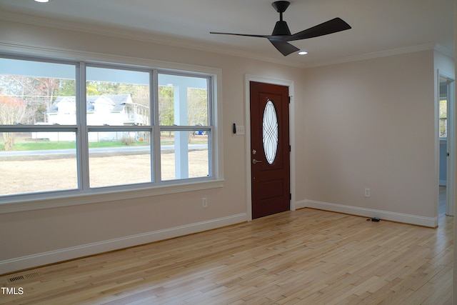 foyer entrance with light wood-style floors, plenty of natural light, and ornamental molding