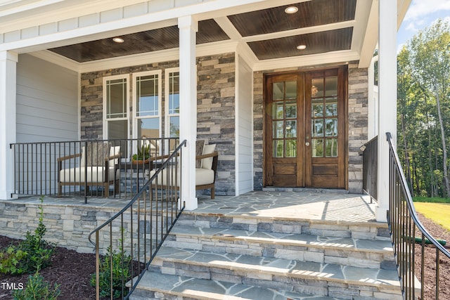 view of exterior entry with covered porch and french doors