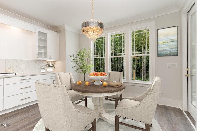 dining area featuring dark hardwood / wood-style flooring, ornamental molding, and an inviting chandelier