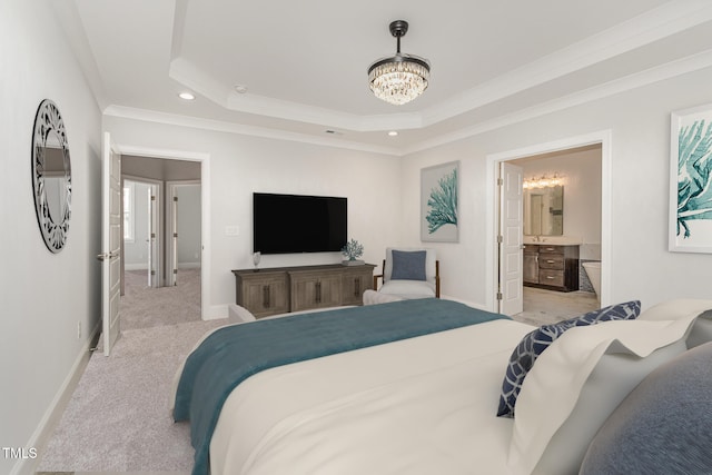 carpeted bedroom featuring a tray ceiling, ensuite bathroom, ornamental molding, and a notable chandelier