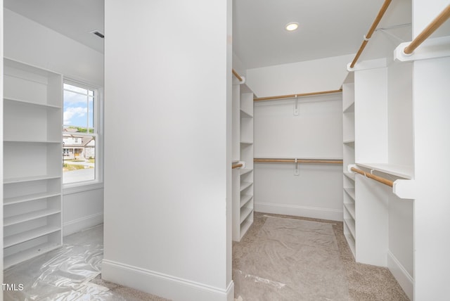 walk in closet with light carpet