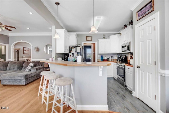 kitchen with a kitchen breakfast bar, white cabinets, stainless steel appliances, and light hardwood / wood-style floors