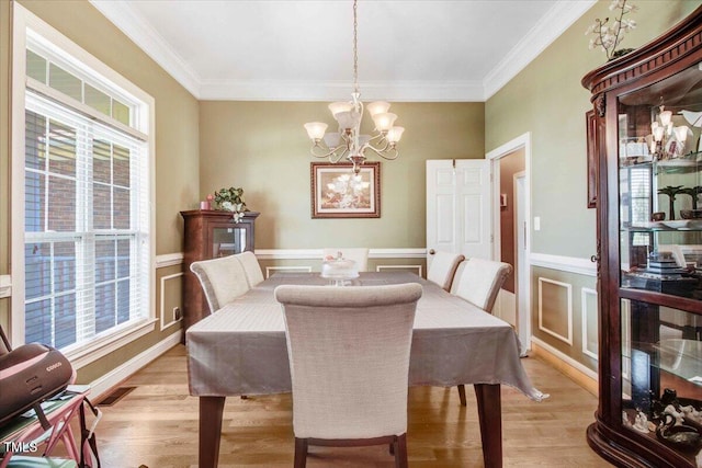 dining space with crown molding, plenty of natural light, and light hardwood / wood-style floors