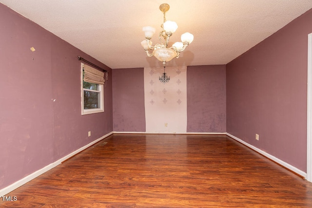 spare room featuring hardwood / wood-style flooring, a textured ceiling, and an inviting chandelier