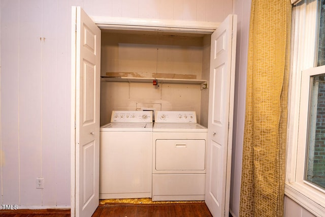 clothes washing area featuring dark wood-type flooring, wooden walls, and washing machine and clothes dryer