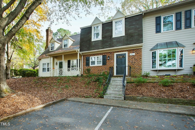1321 Dylan Heath Ct, Raleigh, NC 27608 - view of front of property with a chimney, brick siding, a shingled roof, and uncovered parking