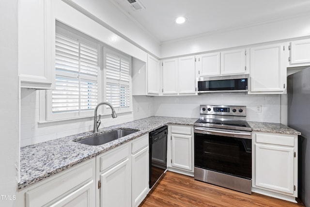 1321 Dylan Heath Ct, Raleigh, NC 27608 - kitchen featuring appliances with stainless steel finishes, white cabinets, light stone countertops, and decorative backsplash