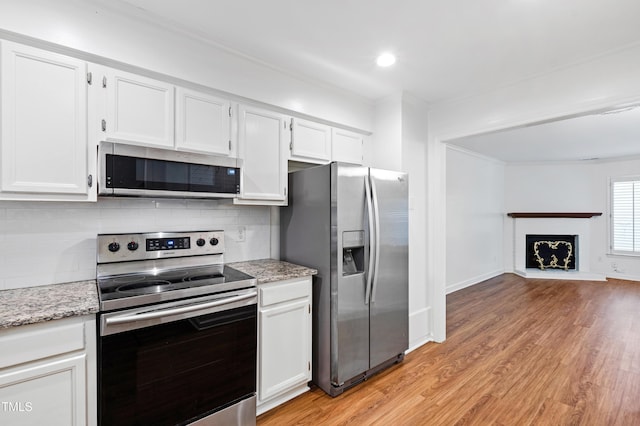 1321 Dylan Heath Ct, Raleigh, NC 27608 - kitchen featuring appliances with stainless steel finishes, ornamental molding, white cabinets, light wood-style floors, and decorative backsplash