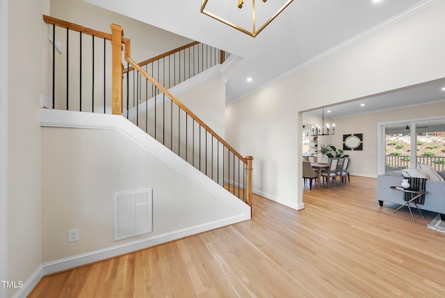 stairs featuring hardwood / wood-style flooring, crown molding, and a notable chandelier