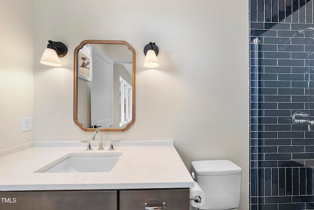 bathroom with a tile shower, vanity, and toilet