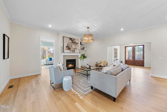 living room featuring french doors, light hardwood / wood-style flooring, plenty of natural light, and ornamental molding