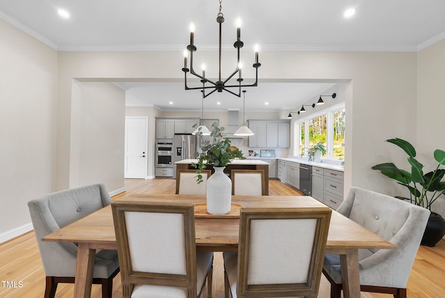 dining room featuring sink, ornamental molding, a notable chandelier, and light wood-type flooring