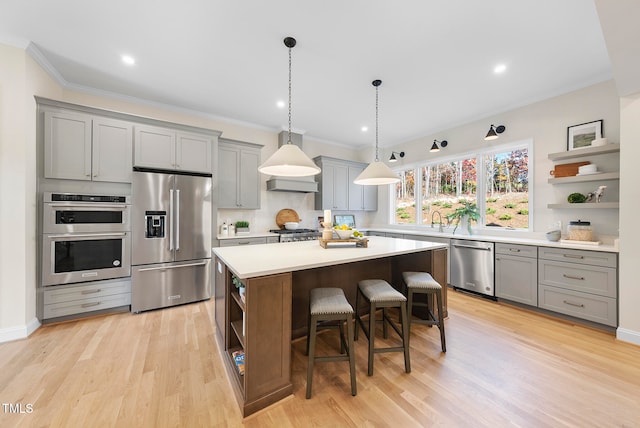 kitchen with appliances with stainless steel finishes, a kitchen island, light hardwood / wood-style flooring, and a kitchen breakfast bar