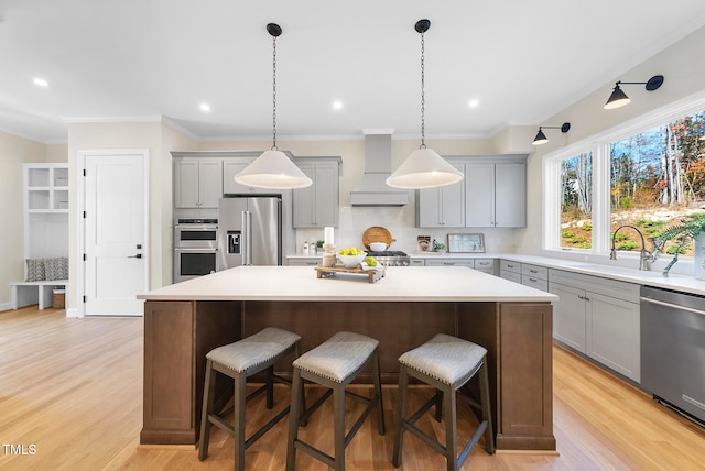 kitchen featuring sink, a kitchen island, stainless steel appliances, and custom range hood