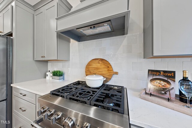 kitchen featuring tasteful backsplash, gray cabinetry, premium range hood, and appliances with stainless steel finishes